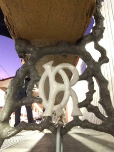 Metal cast letters in cross frame of a seat. 